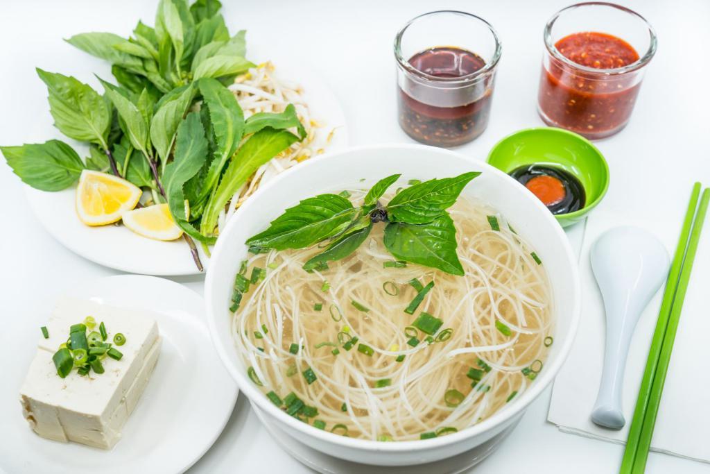 14. Large Tofu Pho Noodle Soup · Vietnamese pho noodle soup served with firm tofu, rice noodle, garnished with green and white onion.