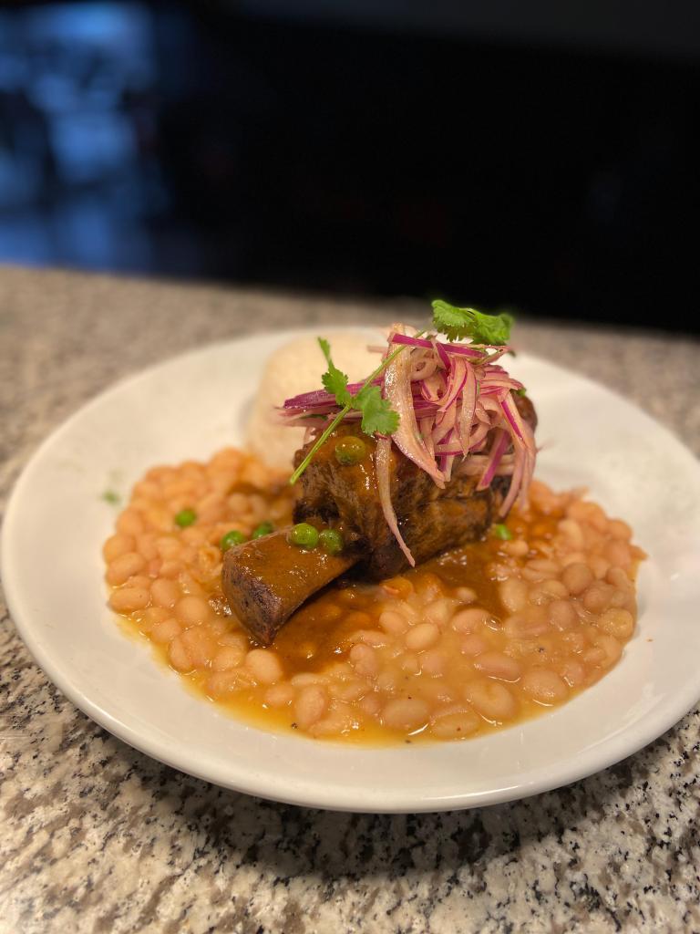 Seco de Res · Slow cooked cilantro braised beef short rib, canary bean, and rice, seco sauce and salsa criolla.