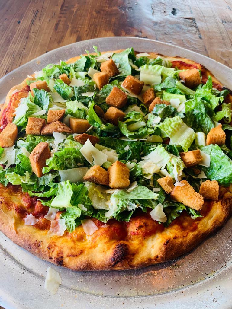Caesar Salad Pie · A Fresh Tomato Basil Sauce Topped with Crisp Romain Lettuce Coated in Our Creamy Caesar Dressing Finished with Imported Parmesan Cheese Shavings & Home Made Croutons