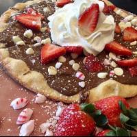 Minter Wonderland Dessert Pizza · Topped with Nutella, fresh strawberries, chocolate chips, peppermint , whipped cream, and po...