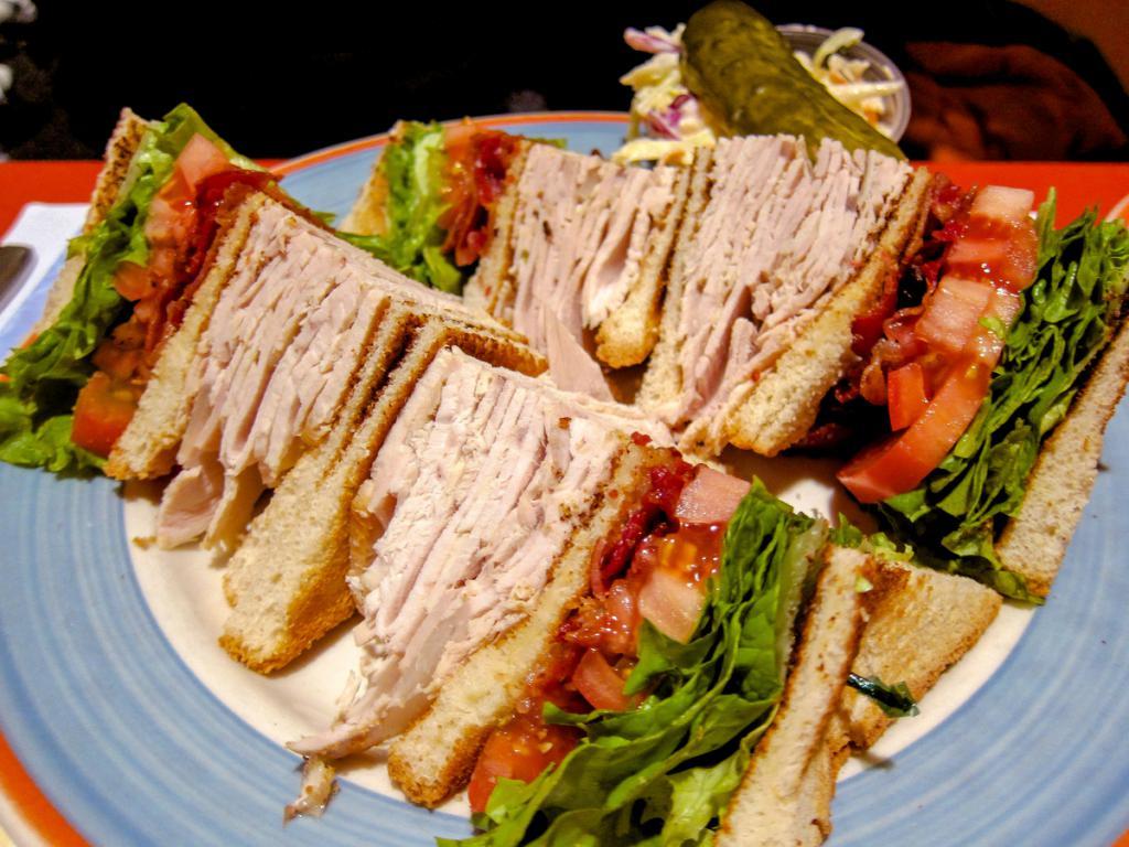 The Club House Sandwich  · Sliced turkey, ham, bacon, lettuce, tomato, mayo and cheese. Served with choice of French Fries, Rosemary Garlic Fries, Tater Tots or Coleslaw. Substitute Onion Rings or Side Salad with Ranch Dressing for $2 more.