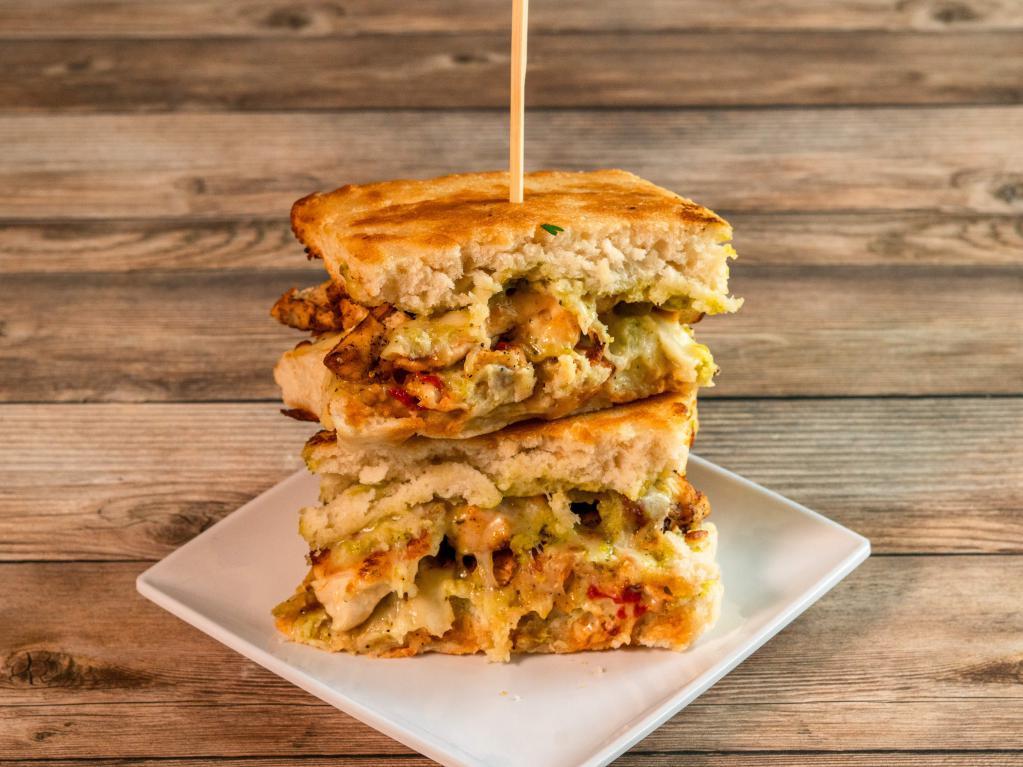 Basil Pesto Chicken Sandwich · Basil pesto drizzled grilled chicken breast with roasted red bell pepper and provolone cheese layered on top and all sandwiched between focaccia bread.