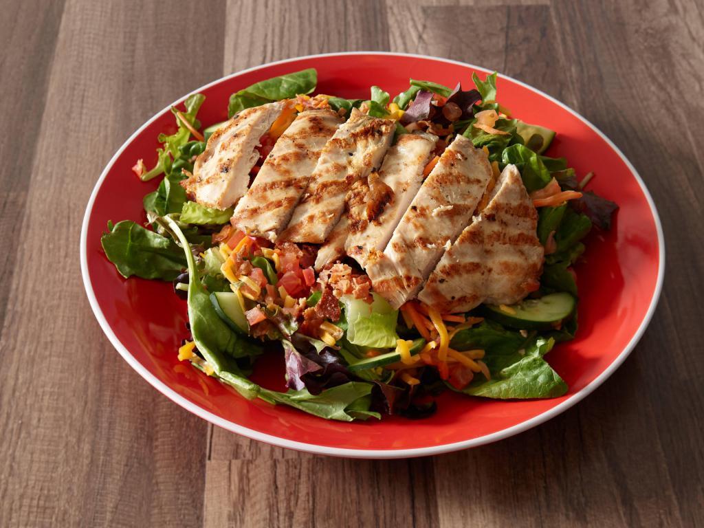 Wood-Fired Grilled Chicken Salad · Mixed greens topped with cheddar cheese, carrots, tomatoes, cucumbers, bacon bits and topped with our wood-fired chicken. Served with your choice of dressing.