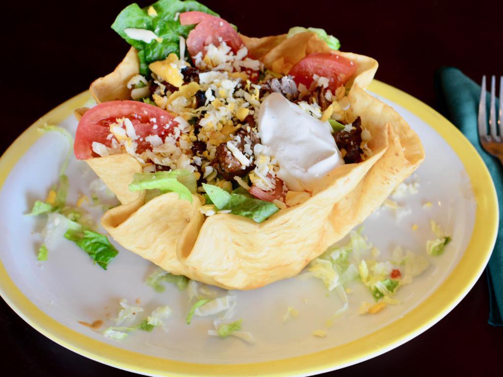Tostada Salad · A large flour tortilla shell filled with chicken or beef, romaine lettuce, tomatoes, shredded cheese and sour cream. Served with homemade dressing on the side.