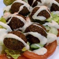 Falafel Salad · Falafel balls on a bed of shredded lettuce, tomatoes, cucumber and pickles topped with tahin...