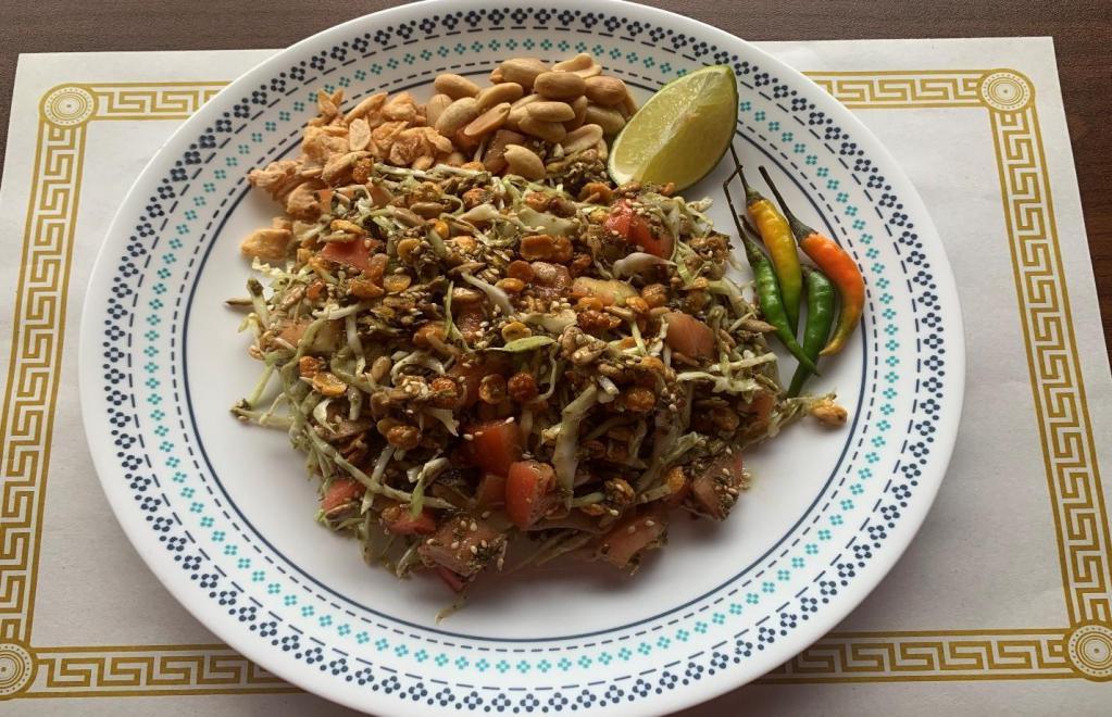 11. Tea Leaf Salad · Burmese tea leaves, cabbage, tomatoes, fried garlic, fried yellow beans, sunflower seeds, peanuts and sesame seeds all mixed and served with 1 slice lime.