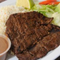 Carne Asada · Grilled rib eye steak served with rice, beans, and 2 tortillas.