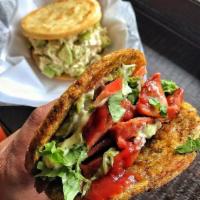 Chorizo Patacon · Twice Fried Green Plantain sandwich with Chorizo topped with lettuce, tomato, fried cheese, ...