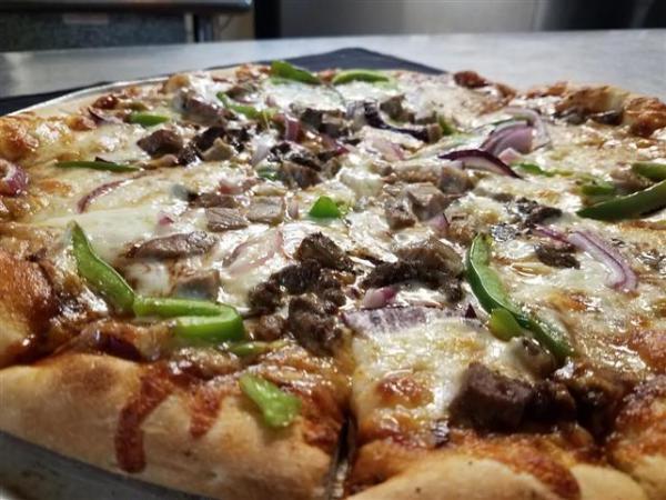 Philly Cheesesteak Pizza · Bianco pizza with mozzarella and provolone cheese, virgin olive oil, hand carved rib eye and green peppers.