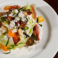 Wedge Salad · Grilled green onion, baby tomato, roasted garlic, crispy prosciutto and creamy bleu cheese.