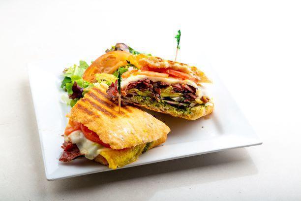 Heart Stopper Panini · Pastrami, egg, avocado, onion, tomato, olives, pesto and your choice of cheese. Includes our house made pesto (nut free), sun-dried tomato, mustard and mayo. Served with a side salad.