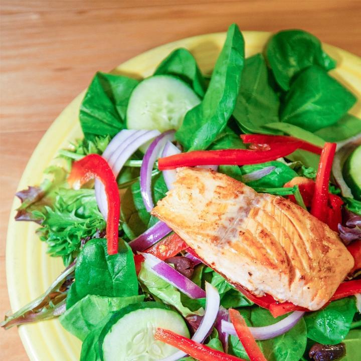 Salmon Salad · Fresh spinach topped with grilled salmon, red onions, fresh red peppers, Kalamata olives, and cucumbers. Served with peppery parmesan dressing on the side.