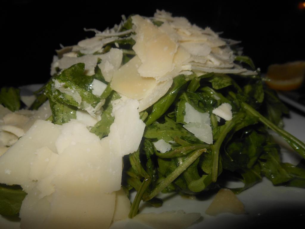 Rughetta Salad · Rugola salad tossed with a lemon dressing topped with shaved Parmesan cheese.