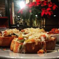 Garlic Bread with Cheese · Sliced French bread loaded with cheese and toasted, served with bruschetta tomatoes and garl...
