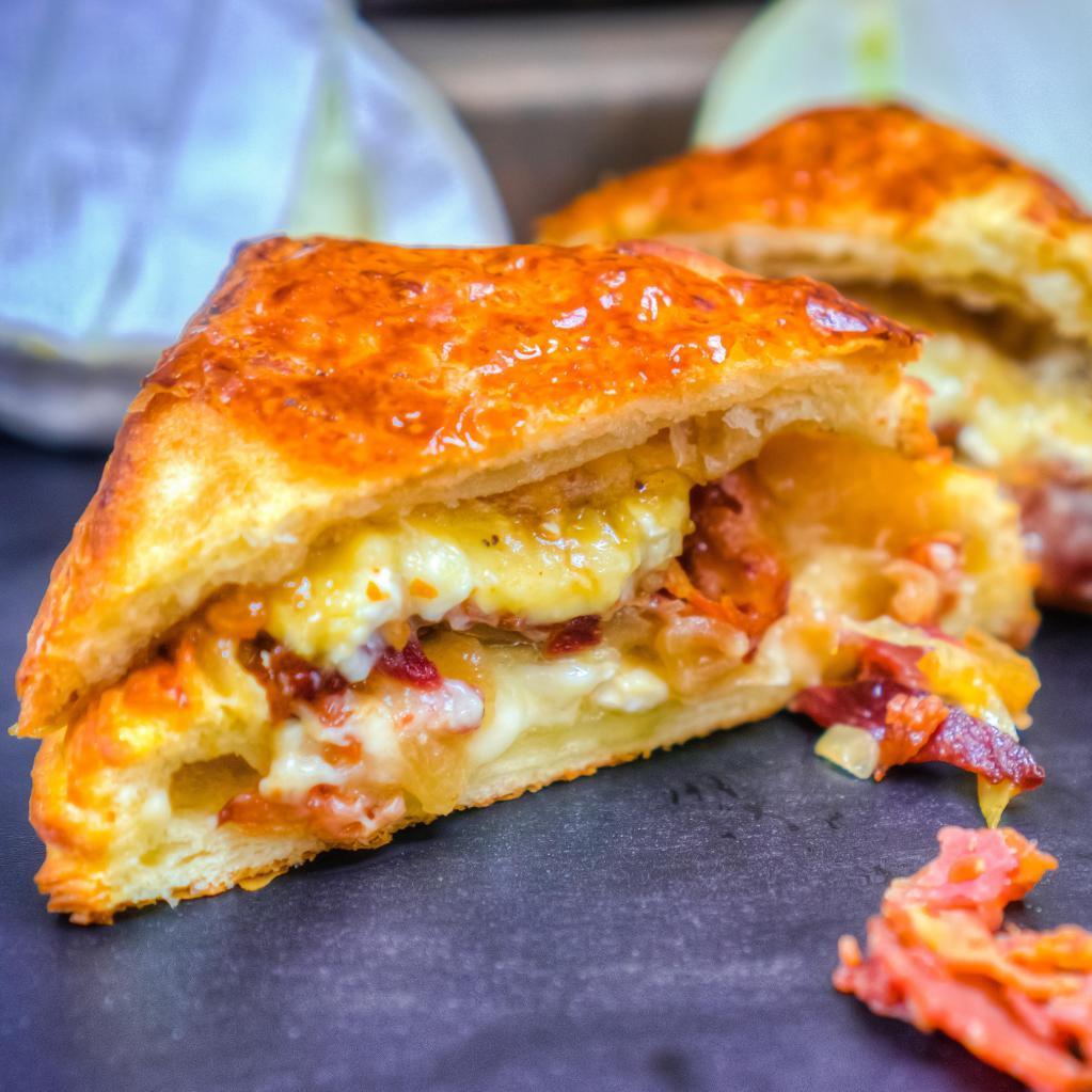 Caramelized Onion and Brie Sandwich · A flaky, house-made croissant bun loaded with crispy bacon, caramelized onions and gooey brie cheese to create the perfect blend of savory and sweet in this delicious croissant sandwich.