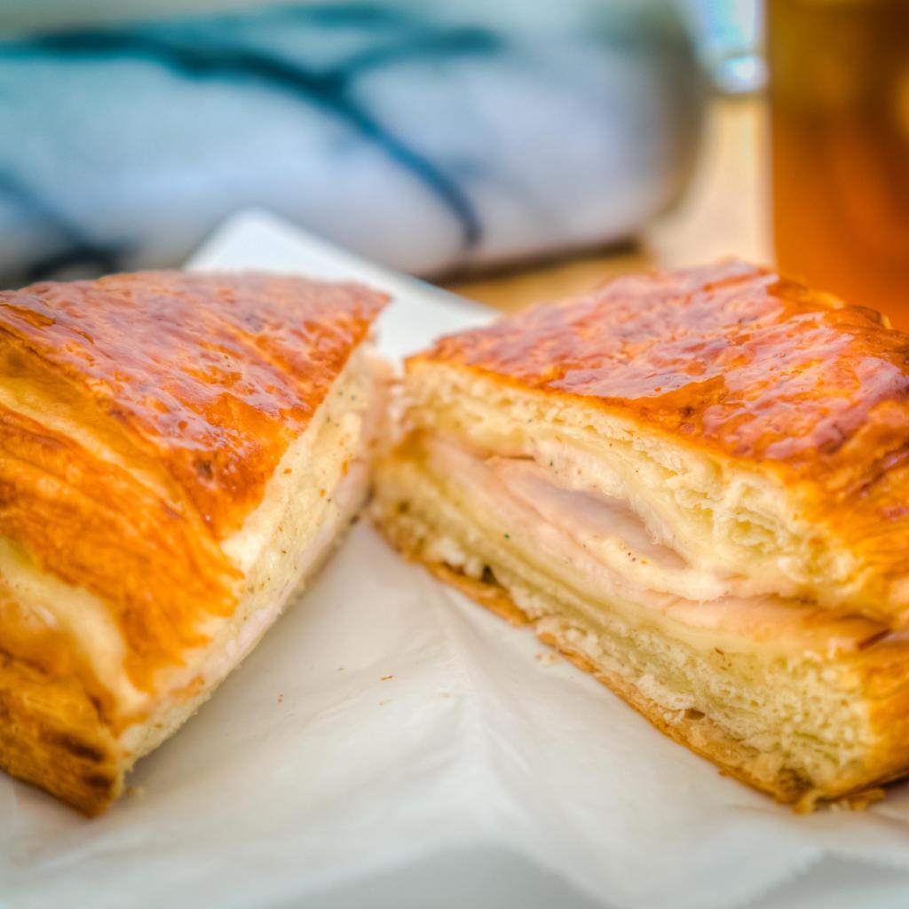 Turkey, Swiss and Garlic Aioli Sandwich · Honey roasted turkey breast, swiss cheese, and house-made garlic aioli spread on top of a flaky, fresh-baked croissant bun. This twist on the classic turkey sandwich is sure to satisfy even the pickiest of eaters!