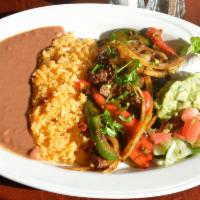 Fajitas de Bistec · Marinated steak with peppers, onions and cilantro. Served with rice and beans, shredded lett...