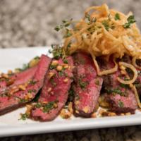 Grilled Herb-Marinated Creekstone Flat Iron Steak · Smoked bacon, Tuscan potatoes, wilted spinach, crispy onion strings, and pine nut-arugula ch...