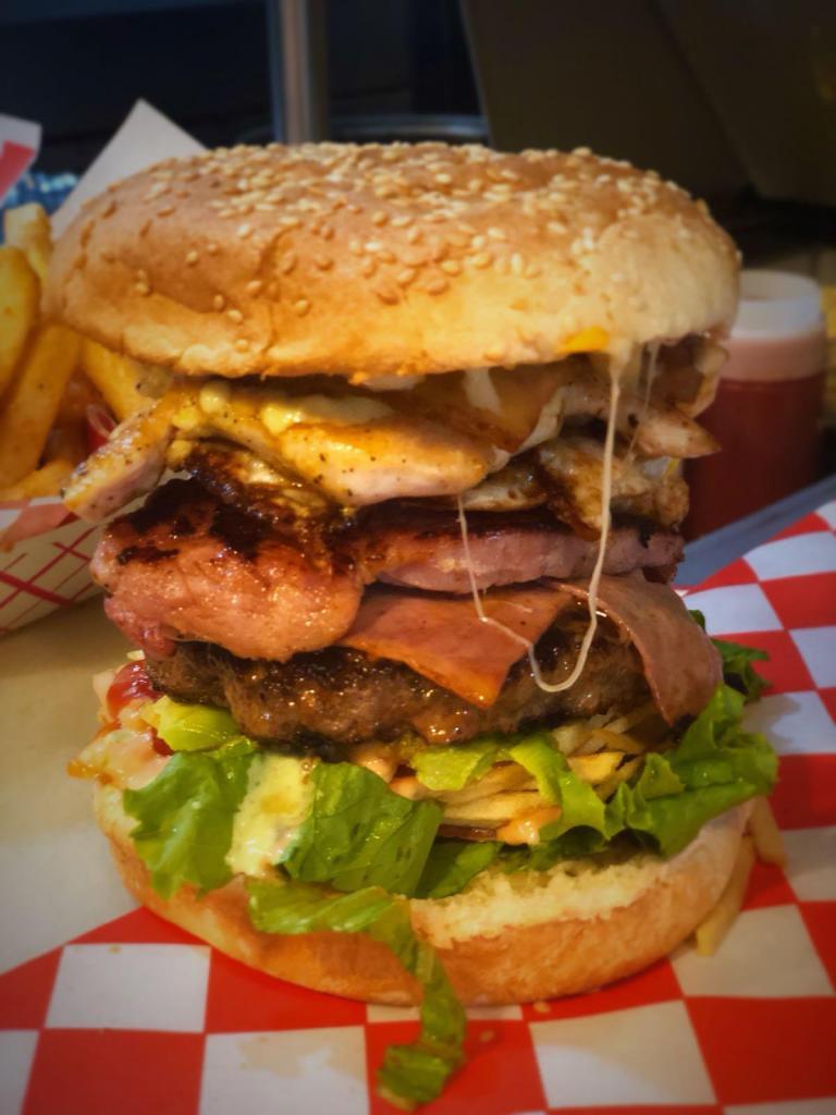 Tripleta Burger · Beef, chicken, smoked pork chop, bacon, ham, cheese, fried egg, avocado, grilled onion, lettuce, tomato, crushed potato chips, ketchup, pink sauce, mayonnaise and mustard.