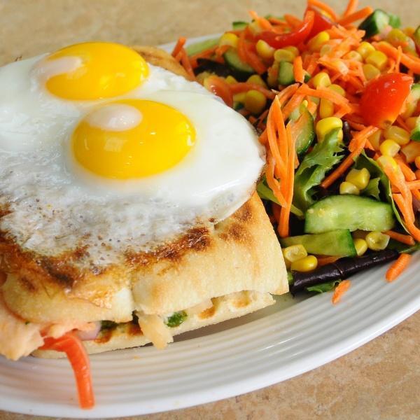 Croque Madame · Grilled cheese sandwich on a ciabatta bread with tomatoes, smoked salmon, pesto sauce and red onions, topped with eggs sunny side up. Served with the house salad.