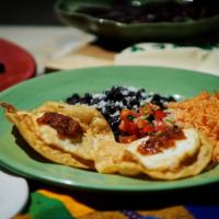 Huevos Rancheros · 2 eggs over fried corn tortilla, tomato rice and refried beans.
