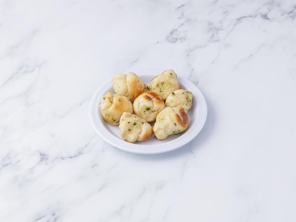 Garlic Knots · 6 pieces. A classic snack, our garlic knots are strips of pizza dough tied in a knot, baked, and then topped with melted butter, garlic, and parsley. Served with a side of sauce.