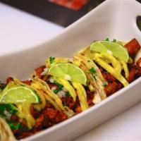 Tacos al Pastor · Three pork tacos marinated with dried peppers & spices, cooked to tenderness served with oni...