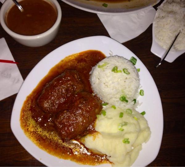 Bife a Role · Tender beef rolled with bacon and carrots, braised with peppers and herbs in a red wine tomato sauce served with potato puree. Includes rice and beans.