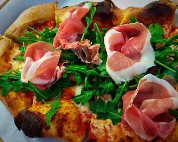 Crudo e Rucola Pizza · 24mo. Parma prosciutto, arugula, tomato sauce, mozzarella, shaved Parmigiano and cherry tomatoes. Napoletana flour.