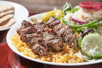 Lamb Skewers (Souvlaki) (3) · Three char-grilled lamb skewers over rice with a Greek salad.
