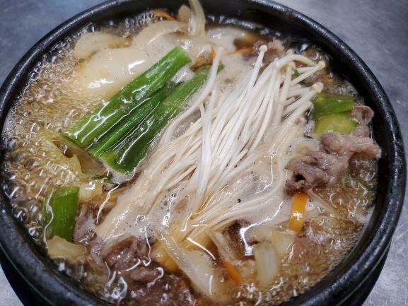 Ttukbaegi Bulgogi · Marinated sliced beef rib-eye cooked with vegetables, mushrooms, rice cakes and glass vermicelli noodle in an earthenware bowl. Very popular item.