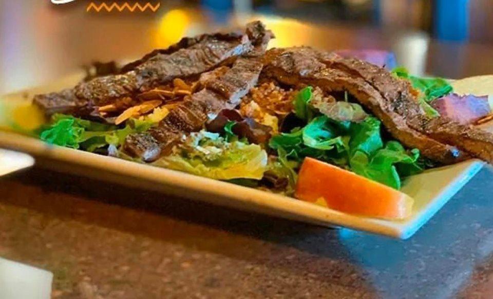 Alegria Salad with Steak · Marinated grilled steak over a bed of spring mix salad, apple slices, bacon bits, shredded cheese, toasted sliced almonds and raw red onions. 