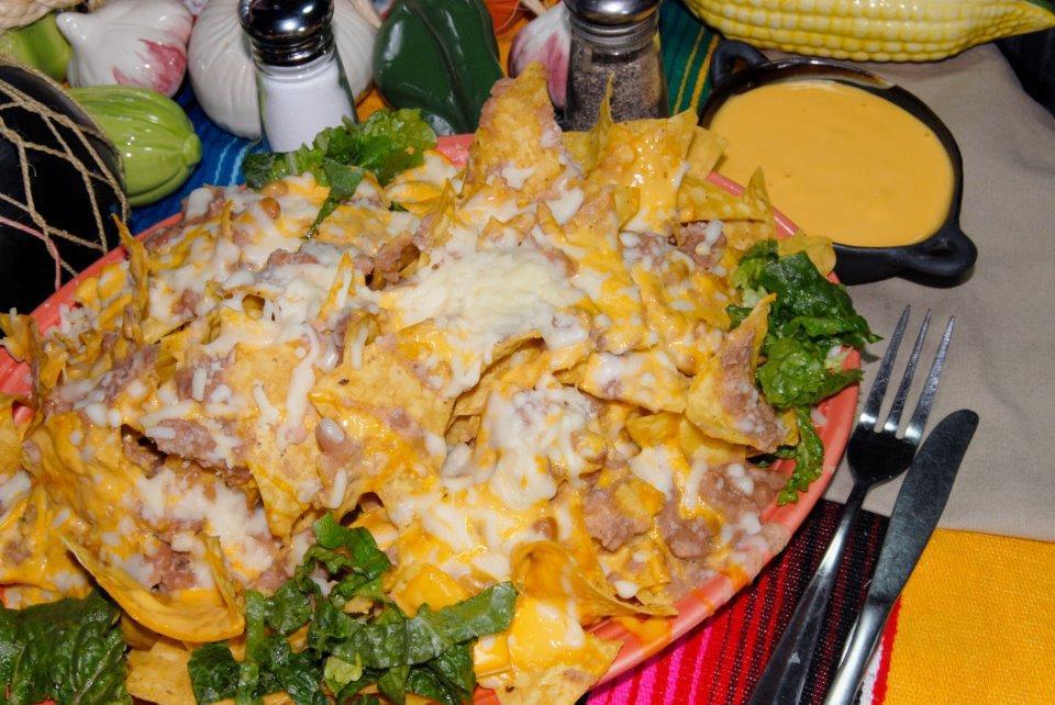 Super Nachos · A mountain of corn chips, smothered in melted jack cheese, beans, lettuce, tomatoes, grilled jalapenos, sour cream and guacamole. Feeds four people. Choose your meat beef, chicken or plain.