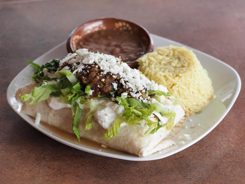 Rib Eye Steak Chimichangas · Marinated in adobo sauce. Flash-fried burrito filled with onions, peppers, cheese and topped with sour cream, salsa, lettuce, queso fresco and served with rice and beans.