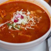 Pozole · Pozole rojo (pork and hominy soup) served with condiments & tortillas.