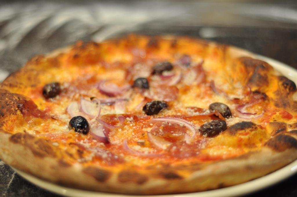 Calabrese Pizza · Onions, kalamata olives, mozzarella, parmigiana, sauce and spicy sopressata.