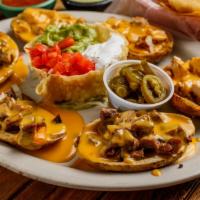 Papa Nachos · 6 potato skins topped with chile con queso, guacamole, sour cream and jalapenos with grilled...