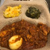 1. Doro Wot · Chicken simmered in a red pepper sauce.  Served with injera and two veggie sides. Spicy.