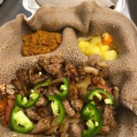 6. Yebeg Tibbs · Lean lamb cubes sautéed in onions, tomato and jalapeno. Served with injera and two veggie si...