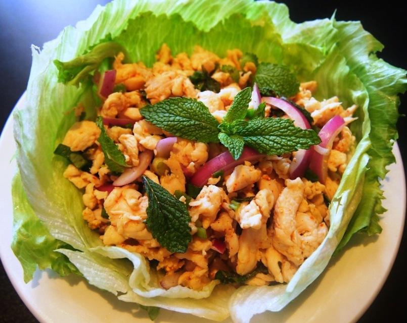 Larb Gai Salad · Ground chicken with red onions, green onion, ground chili pepper in lime and chili juice on a bed of lettuce.
