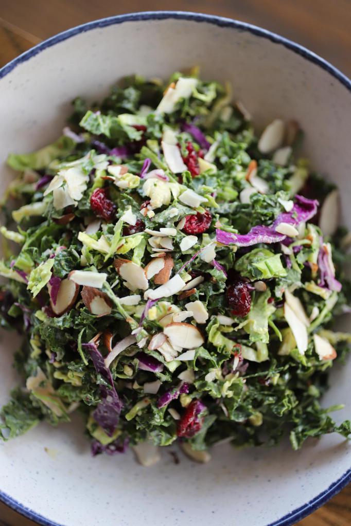 Raw Kale & Brussel Sprout Salad · Kale, Brussel Sprouts, Shaved Parmesan, Almonds, Cabbage, Cherry Tomatoes, Cranberries, Tahini-Maple Dressing