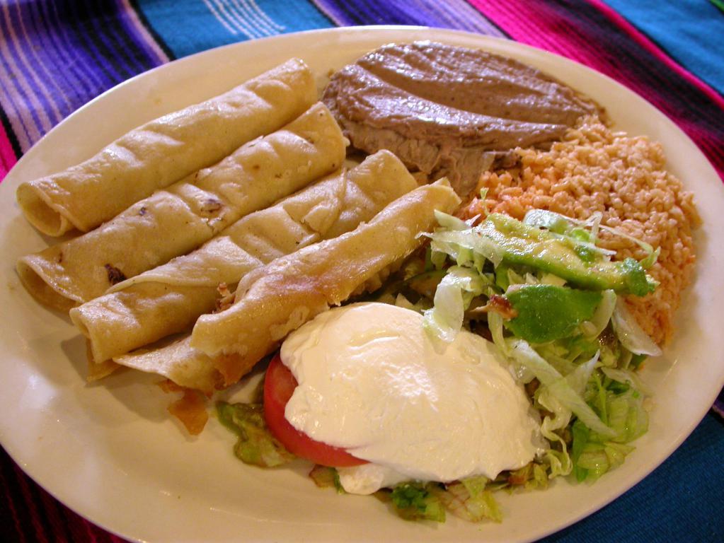 Flautas · Three rolled corn tortillas filled with seasoned shredded chicken or picadillo fried and crispy. Topped with lettuce, tomatoes, guacamole and sour cream. Served with rice and refried beans.