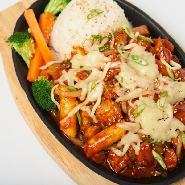 Bull Dak · Spicy chicken stir fried with rice cakes in a fiery sauce, topped with thinly sliced scallions, onions and mozzarella cheese. Served with white rice and steamed vegetables.