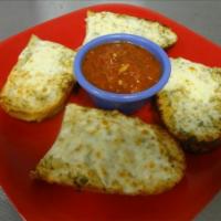 Pesto Garlic Cheese Bread · Toasted sourdough baguette topped with basil pesto, mozzarella and Parmesan with a side of m...