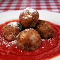 Sicilian Rice Balls · Deep fried rice balls filled with pancetta and mozzarella on a plate of red sauce.