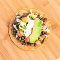 Tostada · Beans, onion, cilantro, lettuce, tomato, sour cream, and avocado, showered with hot sauce.