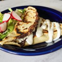 Memelitas de Frijol · Tasty triangle-shaped corn masa stuffed with black beans and cooked on a griddle. Topped wit...