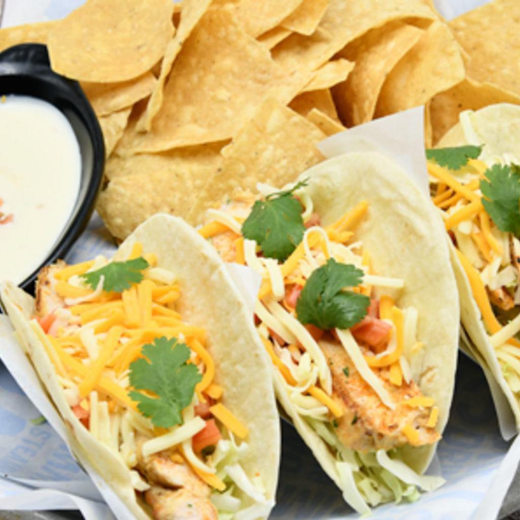 Chicken Tacos · Blackened chicken,  with green cabbage, cilantro, tomatoes, shredded cheese, and avocado lime dressing on flour tortilla. Served with queso and tortilla chips.