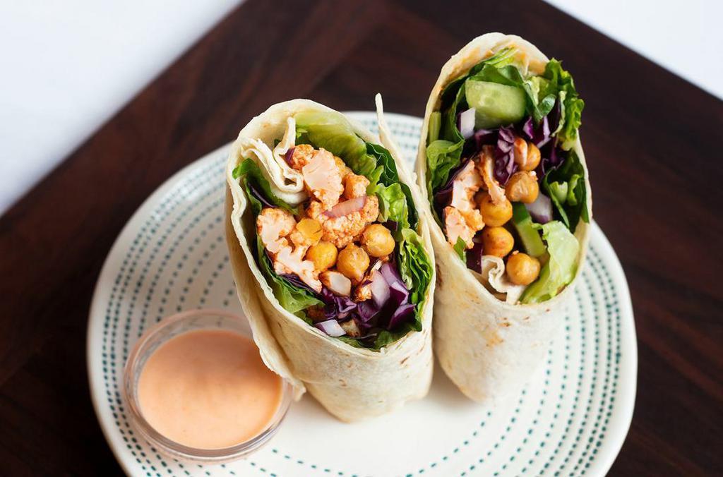 Buffalo Cauliflower & Chickpea Wrap · (vegan, dairy-free) Spicy cauliflower and chickpeas wrapped in a flour tortilla with red cabbage, romaine lettuce, cucumber, red onion, Mama Lil’s peppers, and a touch of garlic. Please no substitutions or modifications.