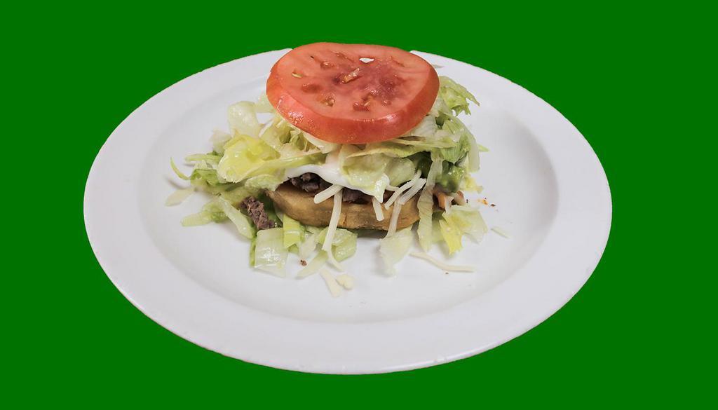 Sope · Fried corn tortilla topped with re-fried beans, choice of meat, lettuce, sour cream, guacamole, cheese and a slice of tomato.